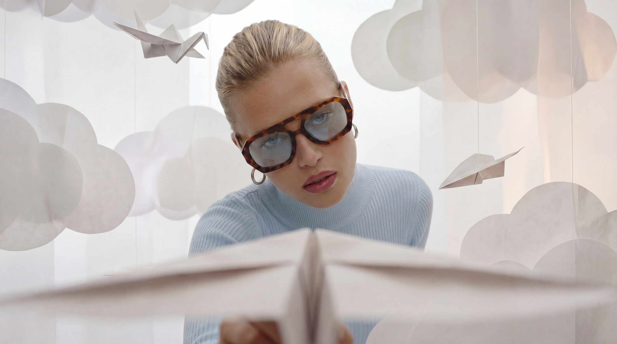 Donna con occhiali da sole che osserva un aeroplano di carta